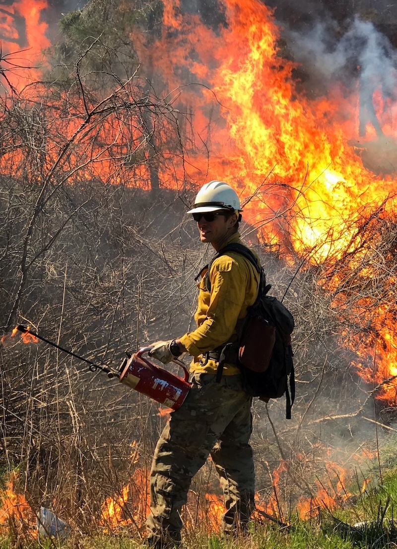 Jess with his drip torch by a forest fire