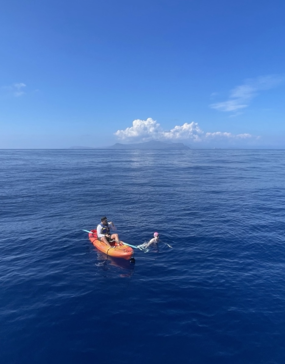 Maya swimming in the ocean with kayak support