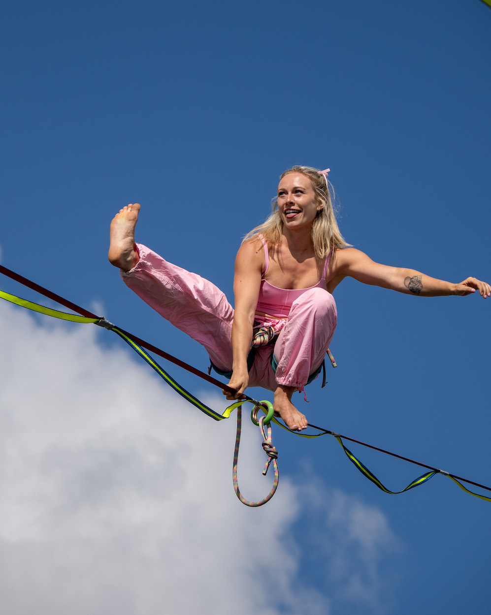 Taylor on her highline in pink against a blue sky