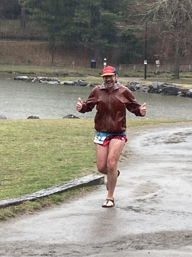 Peter finishing a rainy ultra in his signature sandals for footwear.