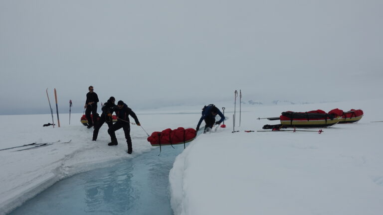 Hefting a loaded sled across an icemelt river.