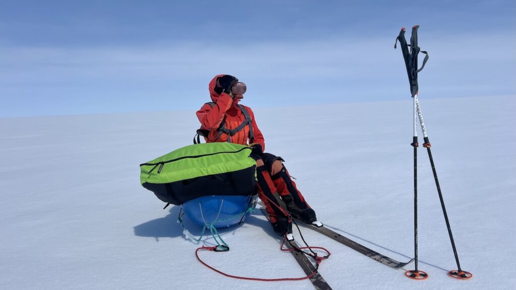 Andrea taking a break sitting on her bright-colored sled with an all-white backdrop