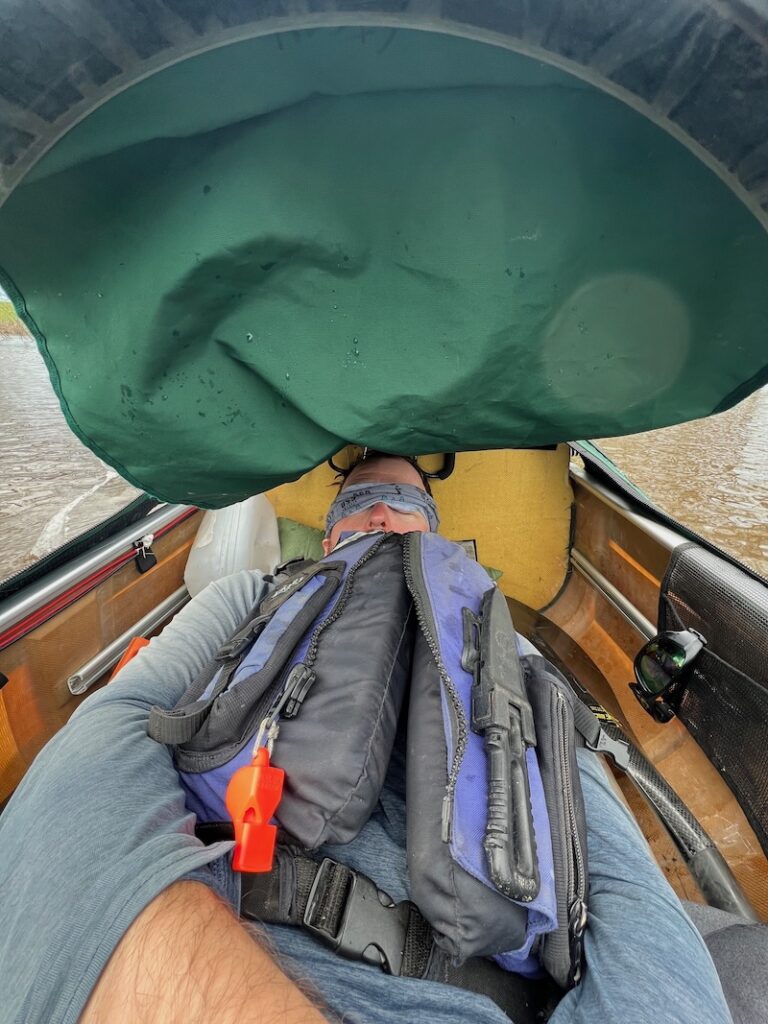 A crew member sleeping in the canoe