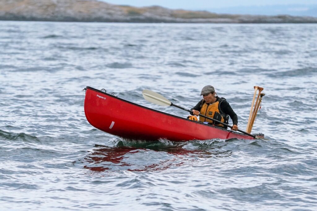 Dianne paddling her red canoe across a lake