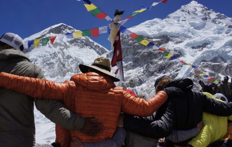 Climbers by prayer flags on Mt. Everest