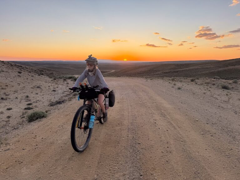 Molly riding a dirt road with a sunset