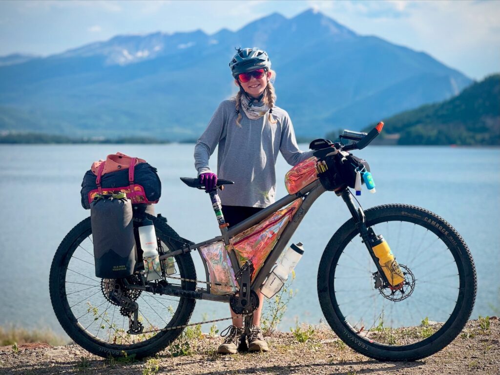 Molly and her bike in a mountain and lake scene