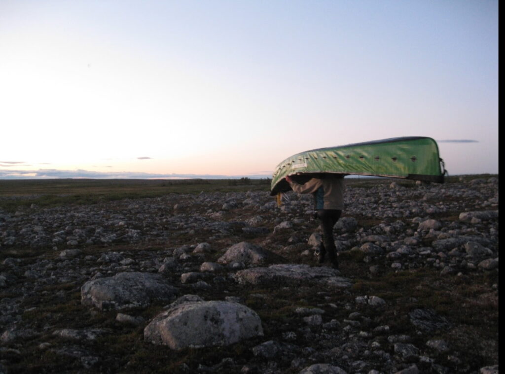 Portaging a canoe over endless rocks and tundra