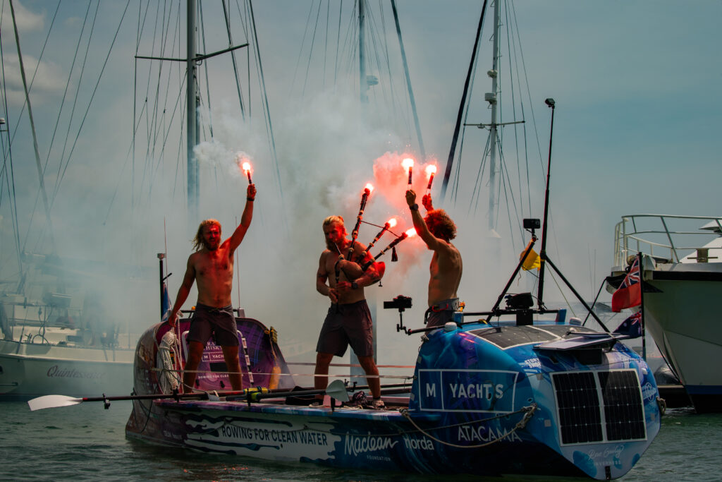 The 3 Maclean brothers celebrating with flares on their boat after completing their ocean crossing