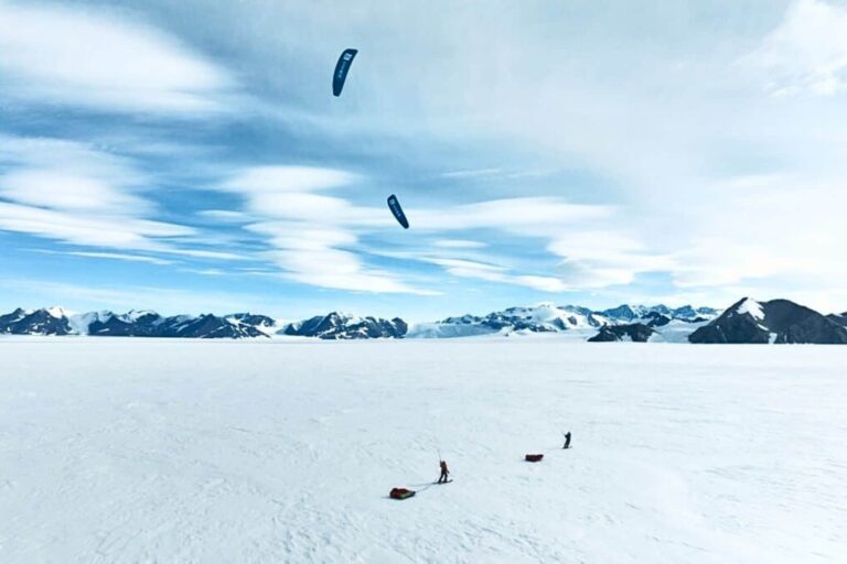 Two tiny kite skiers crossing a massive scene in Antarctica