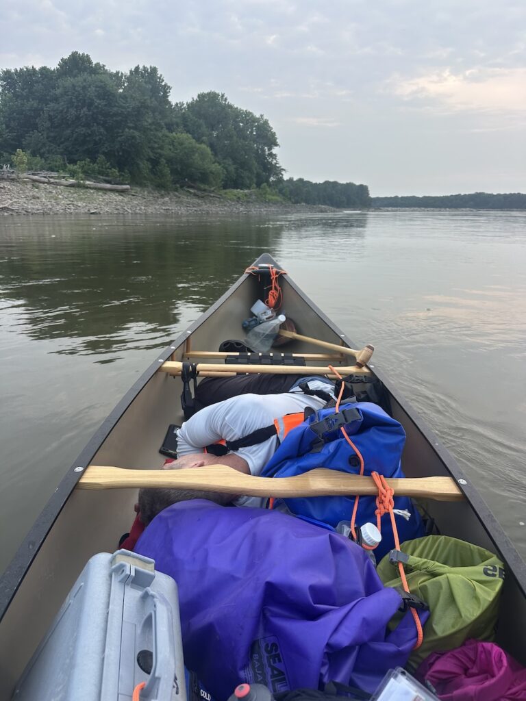 Your host napping in the bottom of the canoe while my canoe-mate paddles solo